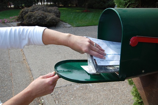 woman getting bills out of mailbox