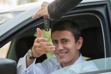 salesman handing car keys to businessman